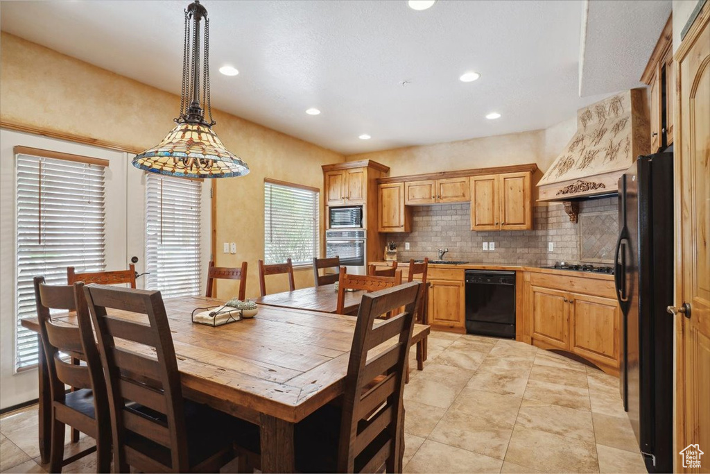Kitchen with tasteful backsplash, recessed lighting, decorative light fixtures, black appliances, and a sink