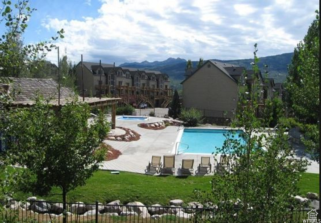 Community pool with a mountain view, fence, and a yard
