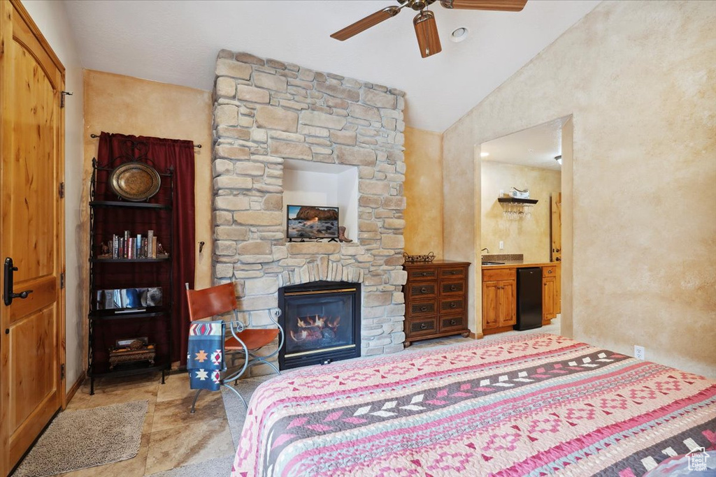 Bedroom featuring a sink, a ceiling fan, a stone fireplace, and lofted ceiling