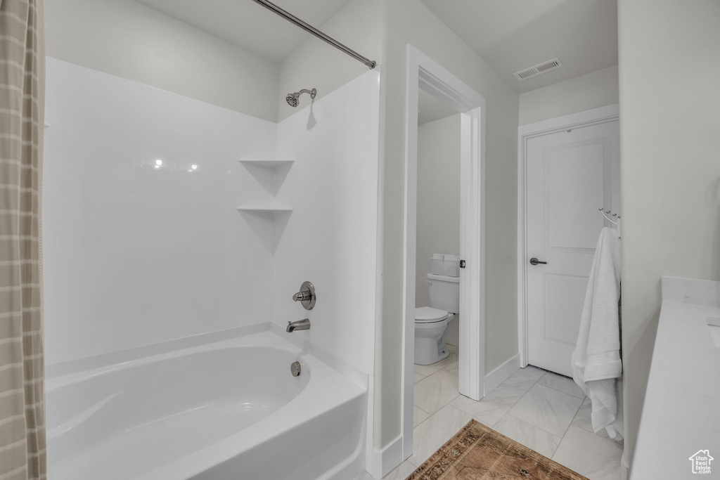 Bathroom featuring marble finish floor, visible vents, toilet, and shower / bathtub combination with curtain