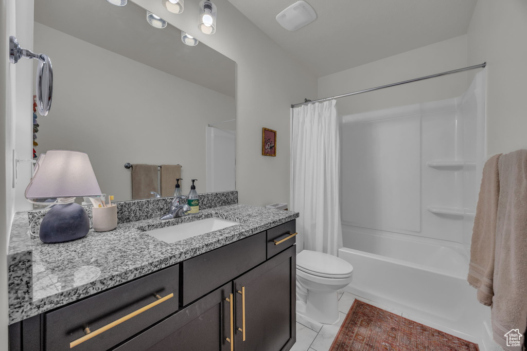 Full bathroom with shower / bath combo with shower curtain, vanity, tile patterned flooring, and toilet
