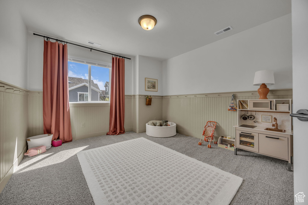 Bedroom featuring a wainscoted wall, visible vents, and carpet