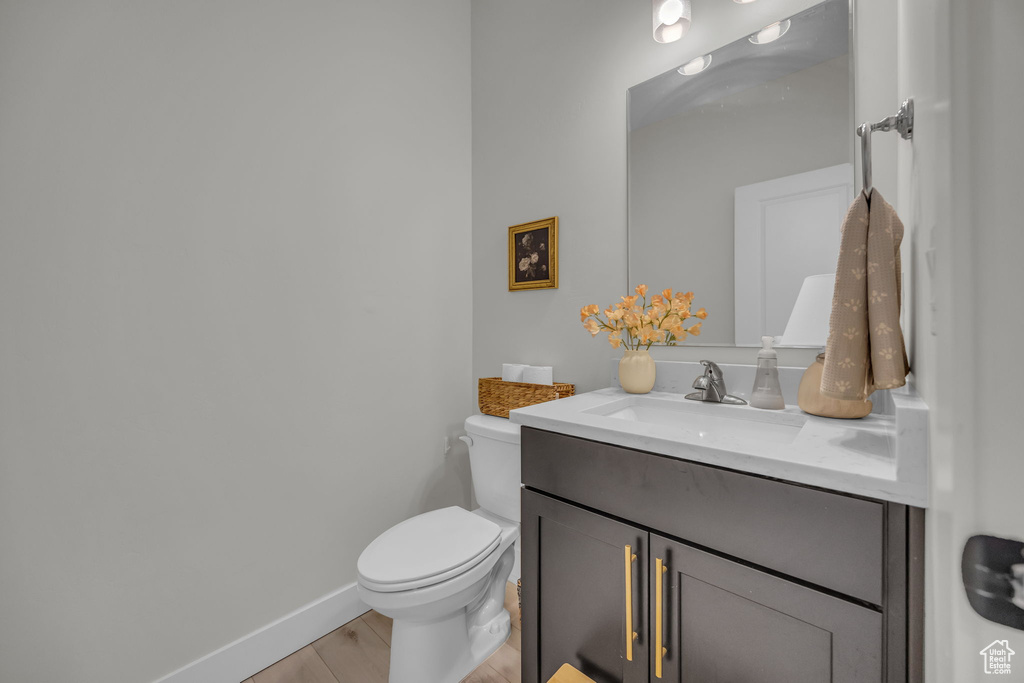 Bathroom with baseboards, wood finished floors, toilet, and vanity