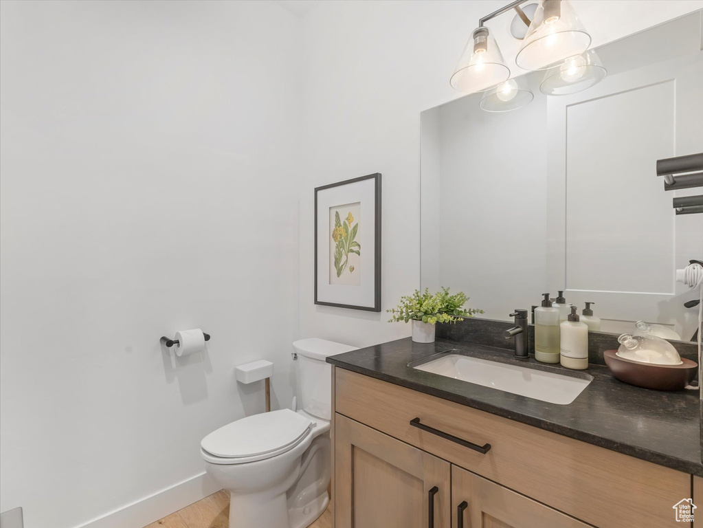 Bathroom featuring vanity, toilet, and baseboards