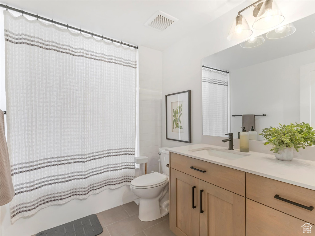Bathroom featuring tile patterned flooring, shower / bathtub combination with curtain, toilet, vanity, and visible vents