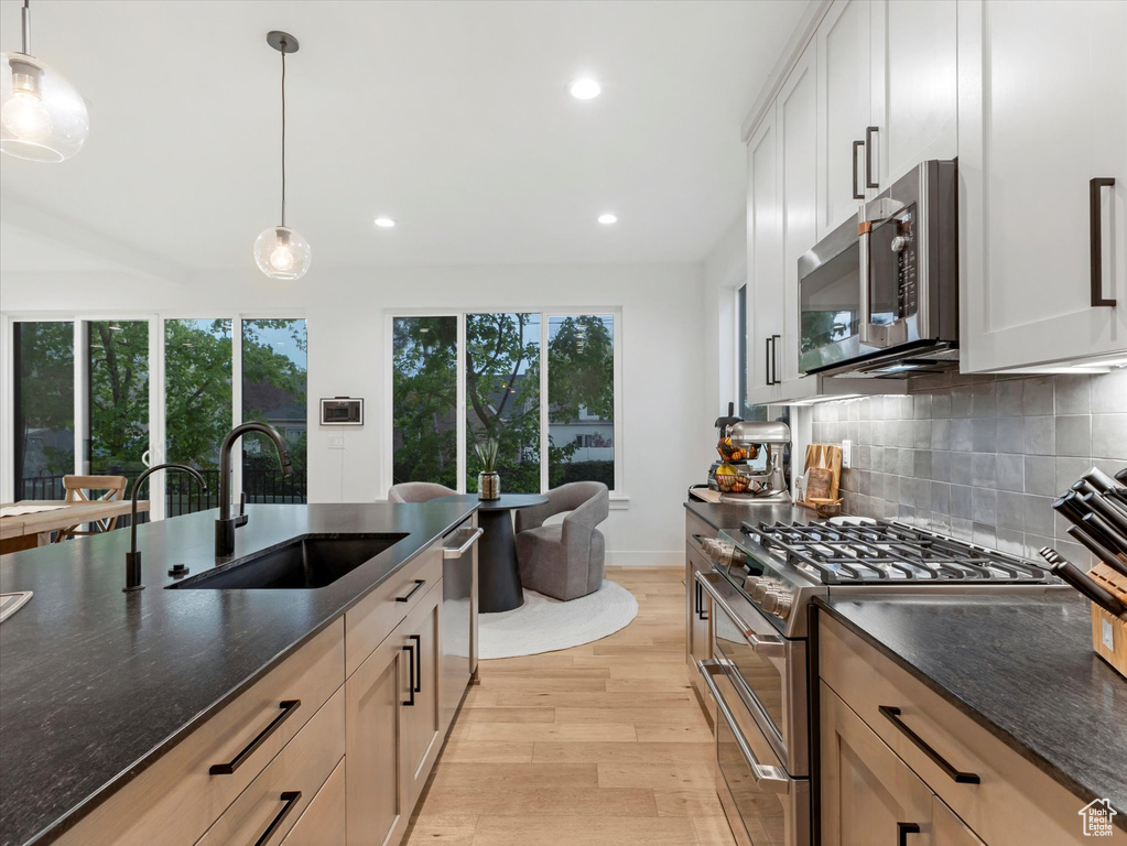Kitchen with recessed lighting, a sink, light wood-style floors, tasteful backsplash, and appliances with stainless steel finishes