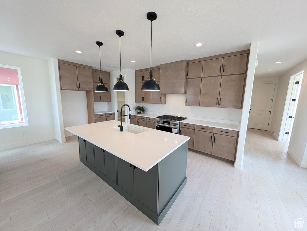 Kitchen with a sink, stainless steel gas range, light countertops, baseboards, and recessed lighting