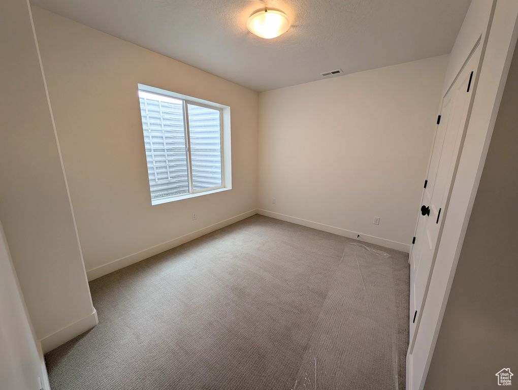 Unfurnished bedroom featuring visible vents, baseboards, and light carpet