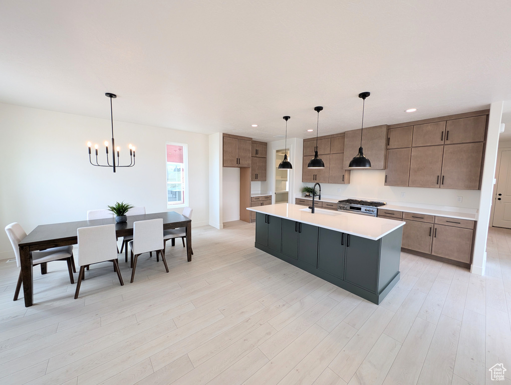Kitchen with a chandelier, light countertops, a sink, stove, and light wood finished floors