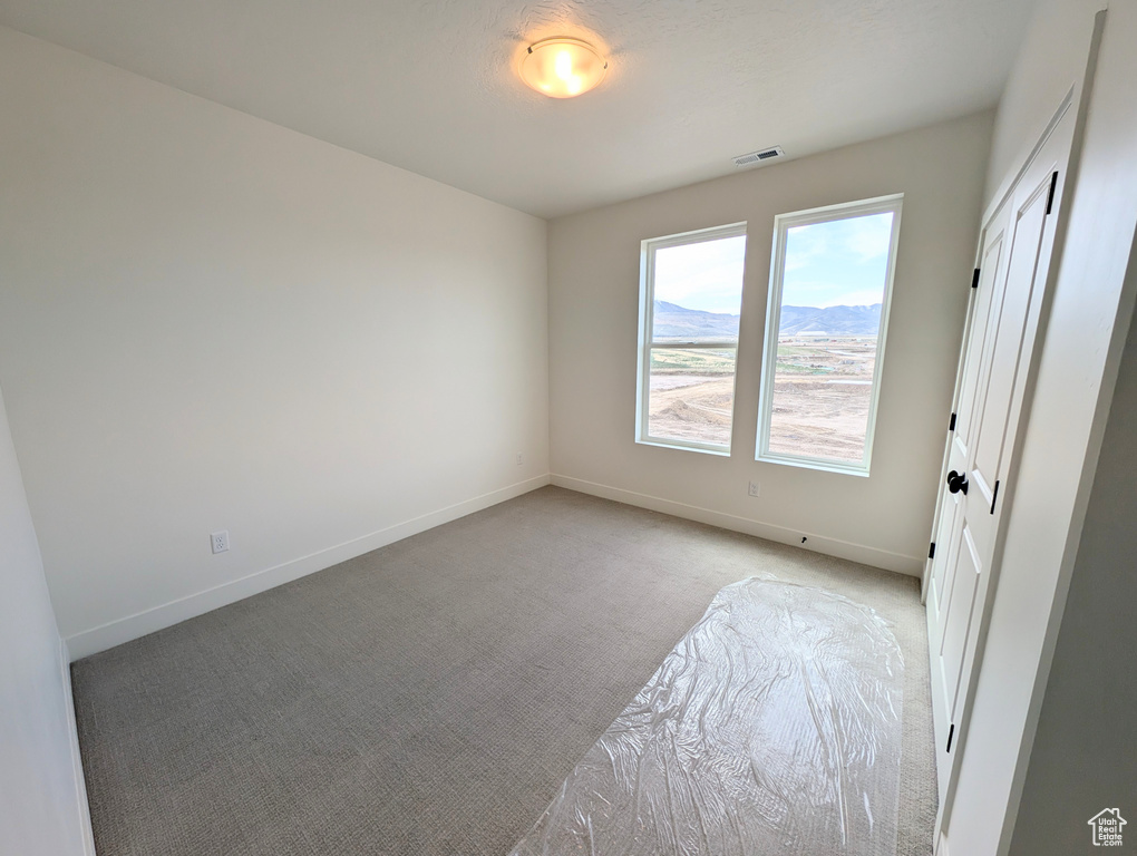 Unfurnished room with light carpet, visible vents, and baseboards