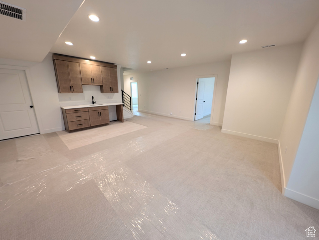 Unfurnished living room with recessed lighting, wet bar, visible vents, baseboards, and light colored carpet