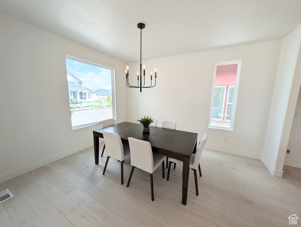 Dining area with a chandelier, light wood-style floors, and baseboards