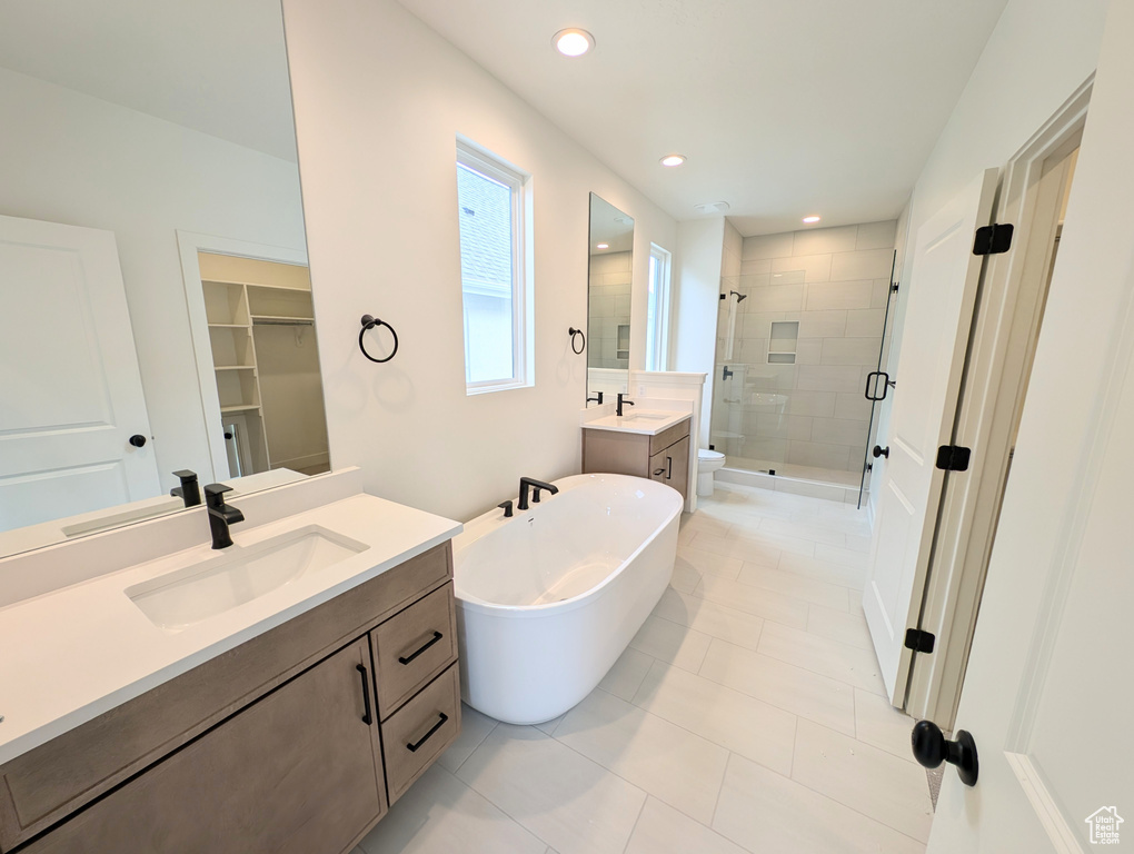 Bathroom featuring two vanities, a soaking tub, a sink, and a stall shower