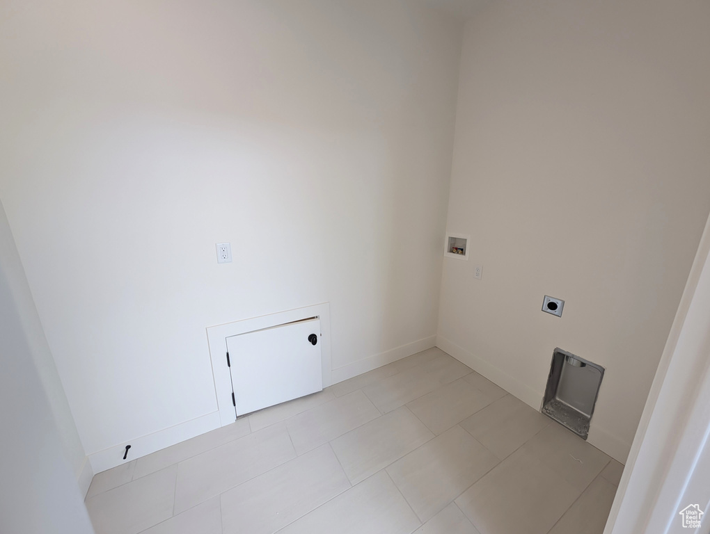 Laundry area featuring hookup for an electric dryer, light tile patterned floors, baseboards, laundry area, and washer hookup