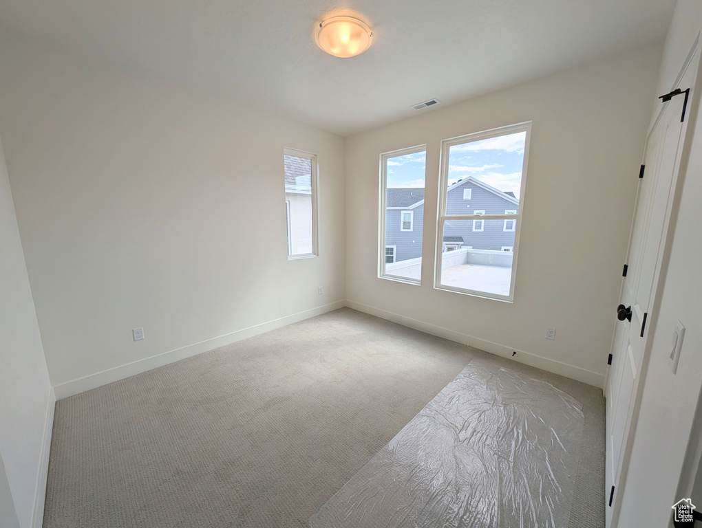 Unfurnished bedroom featuring light colored carpet, baseboards, and visible vents