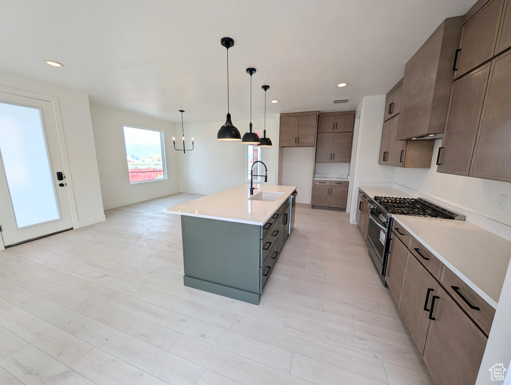 Kitchen with hanging light fixtures, a sink, light countertops, gas stove, and recessed lighting