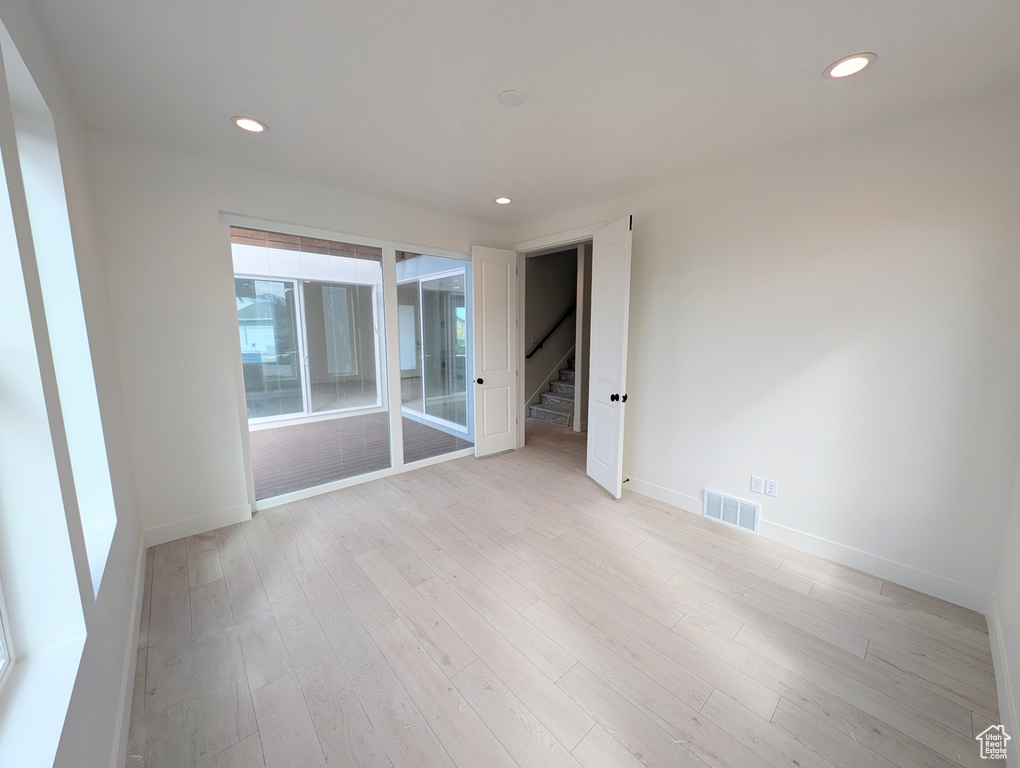 Empty room featuring stairway, visible vents, and baseboards