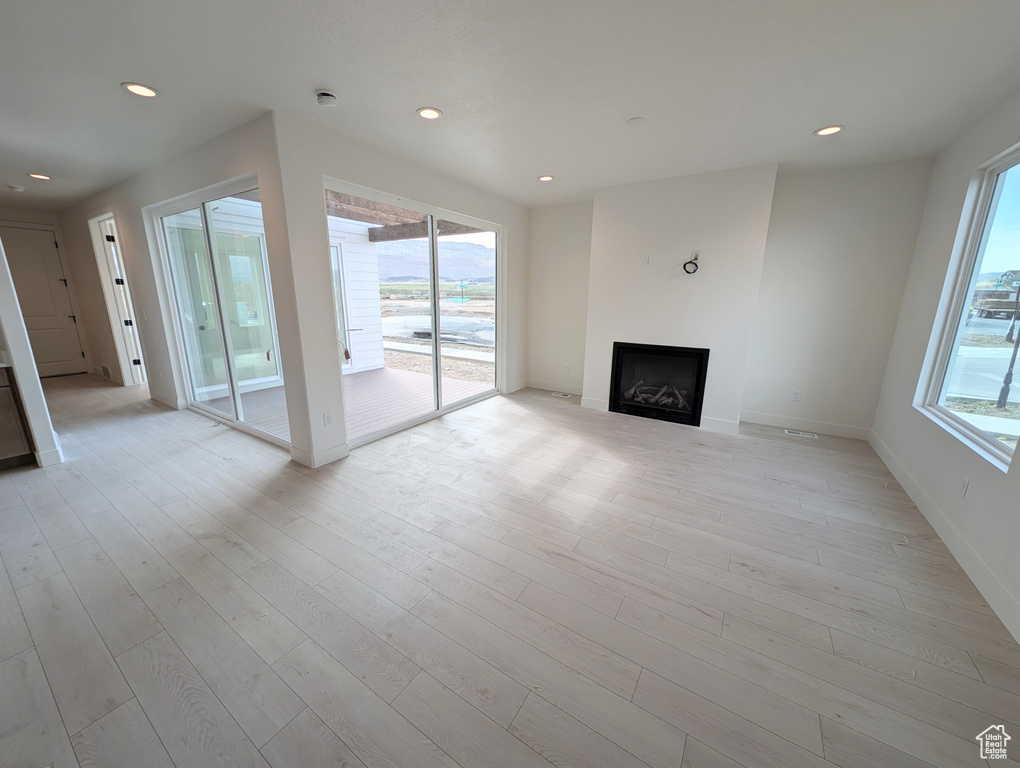 Unfurnished living room with a fireplace, plenty of natural light, light wood-type flooring, and recessed lighting