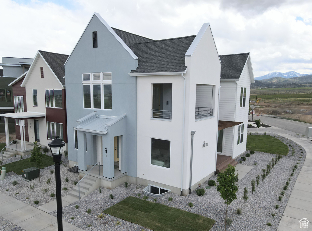 View of front of property featuring roof with shingles, stucco siding, and a mountain view