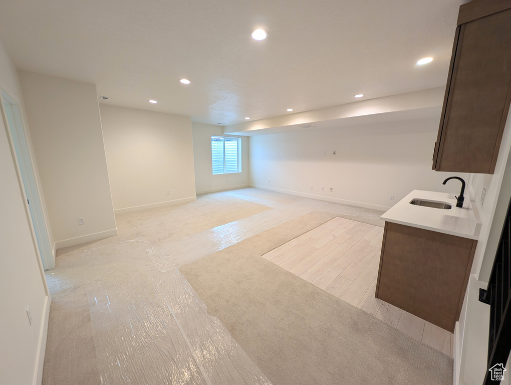 Basement with baseboards, light wood-style floors, a sink, and recessed lighting