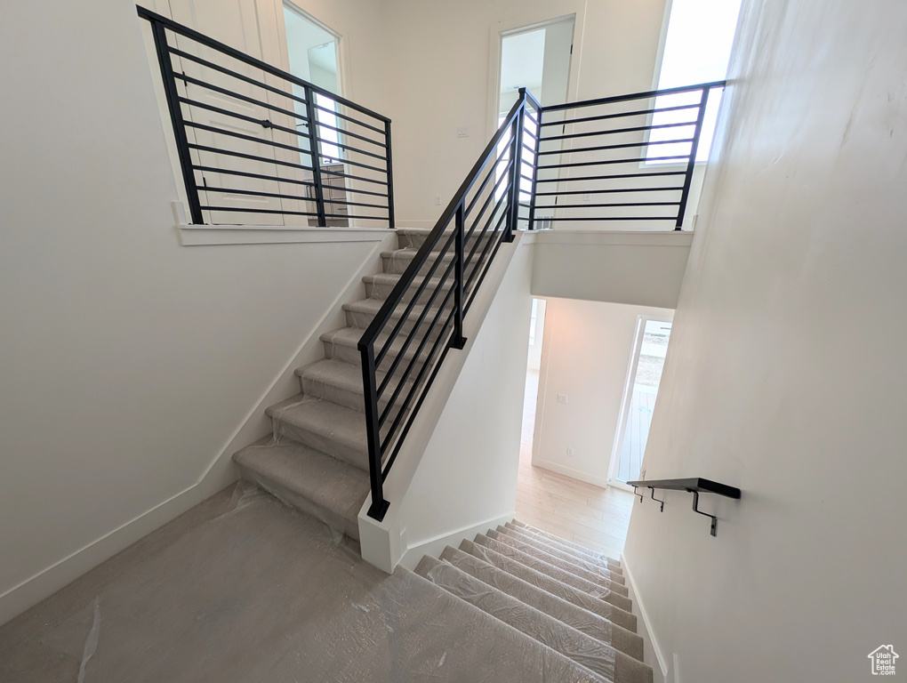 Stairway featuring a towering ceiling and baseboards