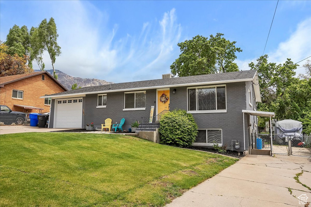 Ranch-style home with an attached garage, a front lawn, fence, and driveway