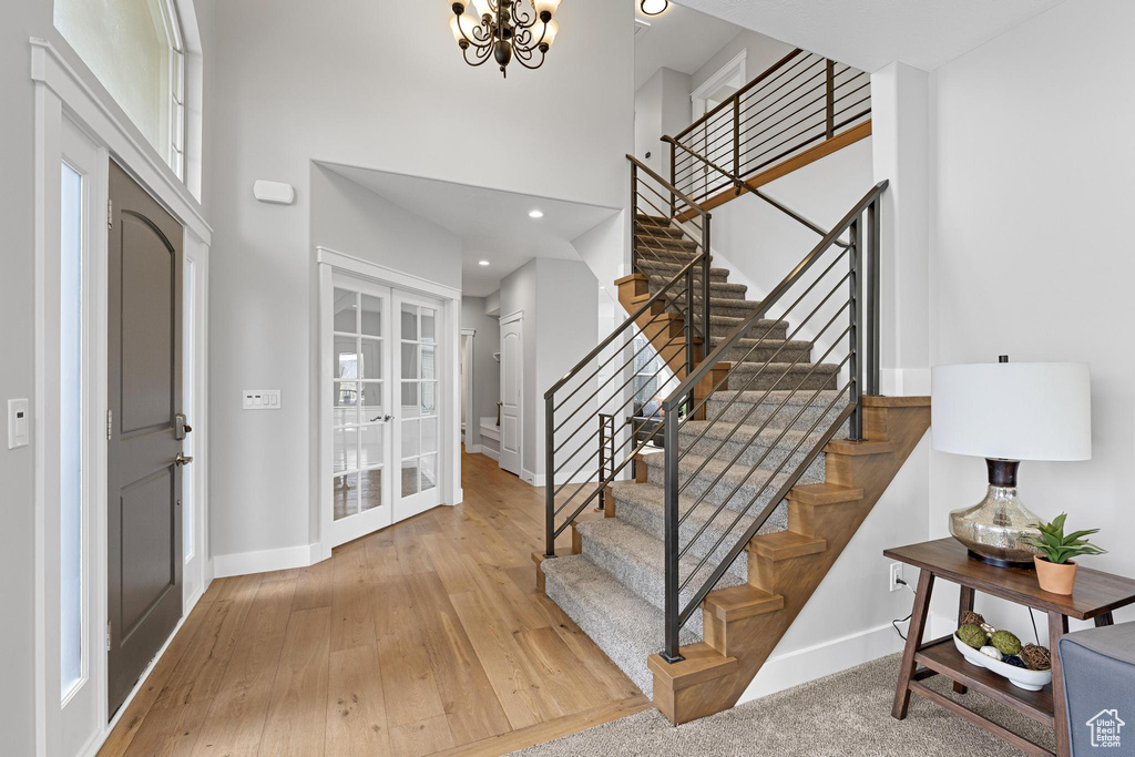 Foyer entrance featuring stairs, wood-type flooring, baseboards, a high ceiling, and french doors