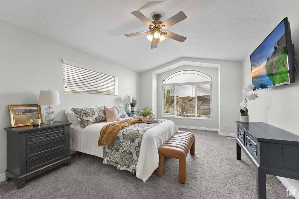 Carpeted bedroom featuring baseboards, ceiling fan, and vaulted ceiling