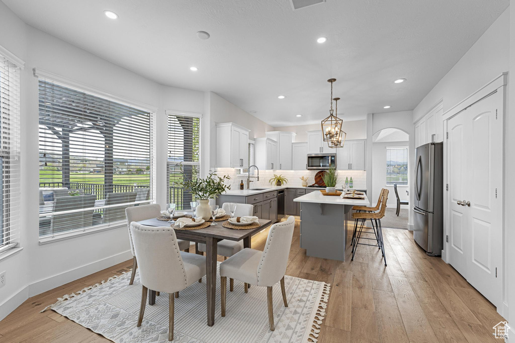 Dining area featuring light wood-style floors, recessed lighting, baseboards, and arched walkways