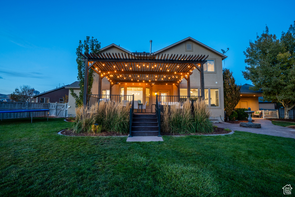 View of front of house with fence, stucco siding, a front yard, and a pergola