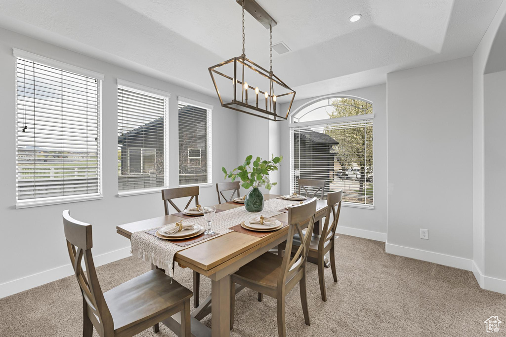 Dining space featuring baseboards, light carpet, an inviting chandelier, and vaulted ceiling