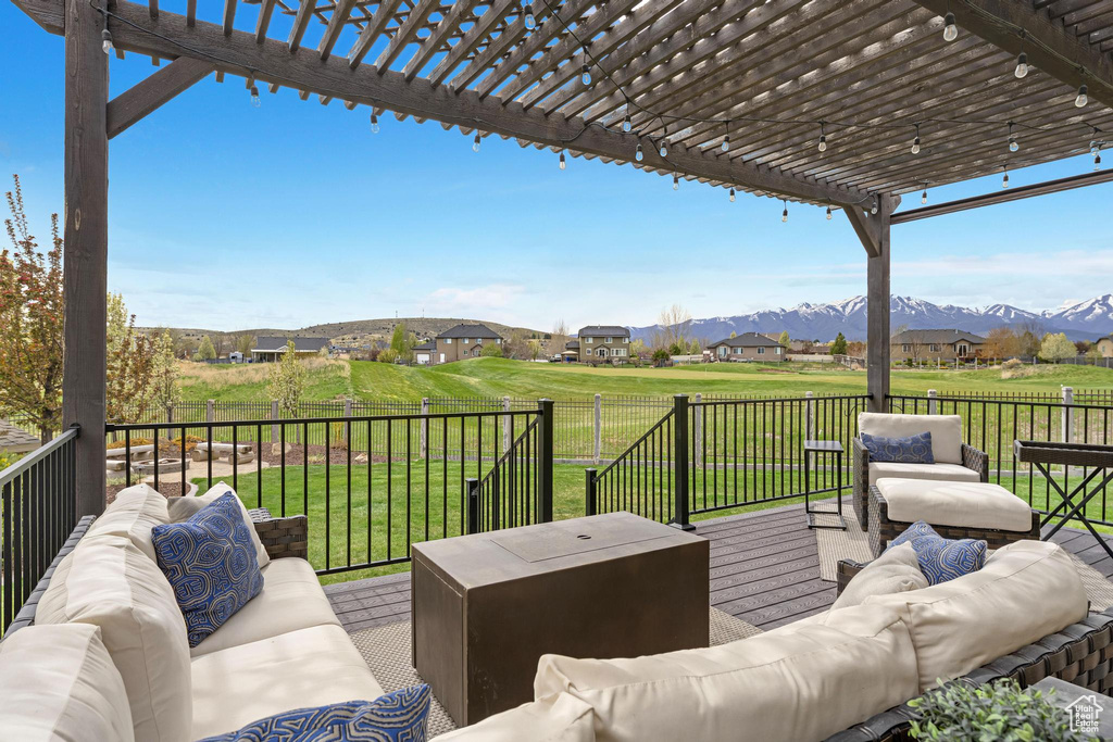 Deck featuring a pergola, a residential view, an outdoor living space, a lawn, and a mountain view