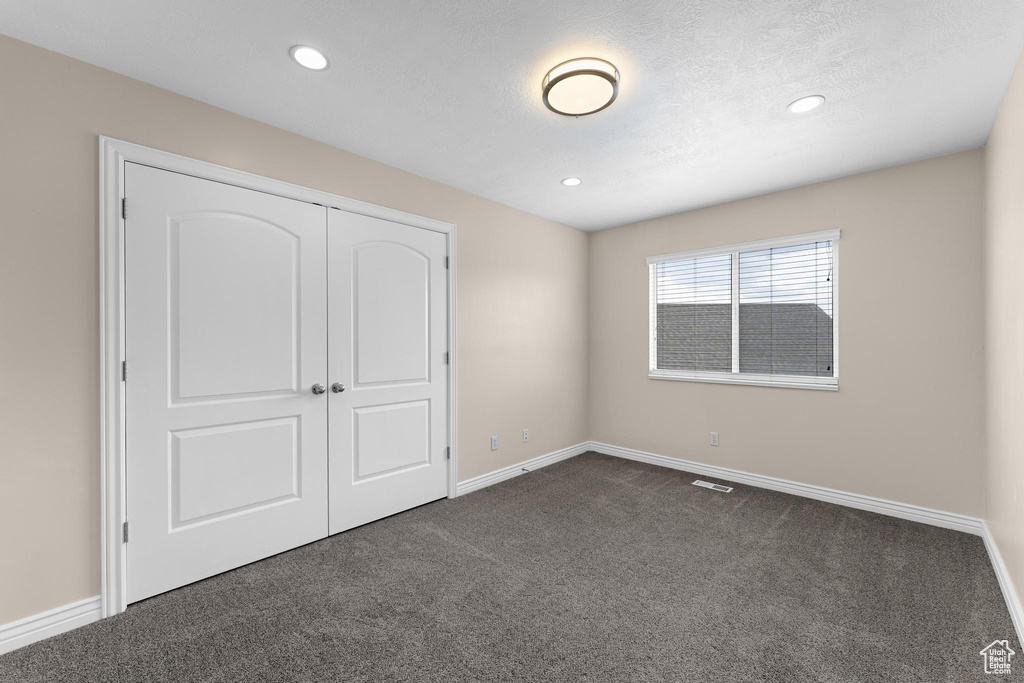 Unfurnished bedroom featuring recessed lighting, a closet, baseboards, visible vents, and dark carpet