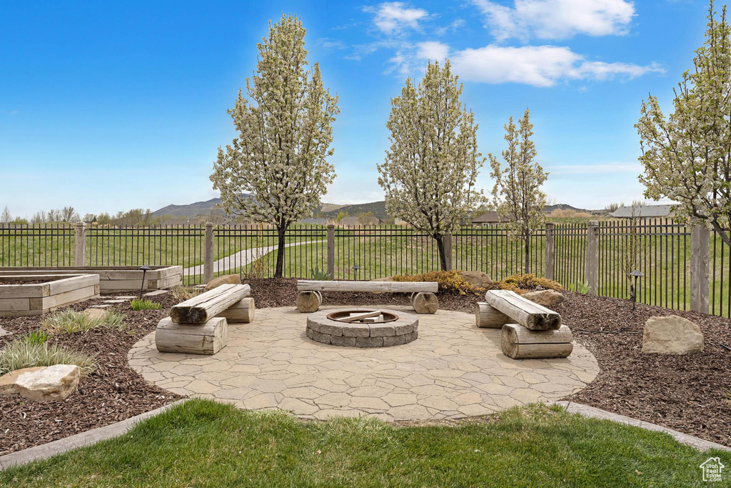 View of patio featuring a fire pit, fence private yard, a mountain view, and a garden