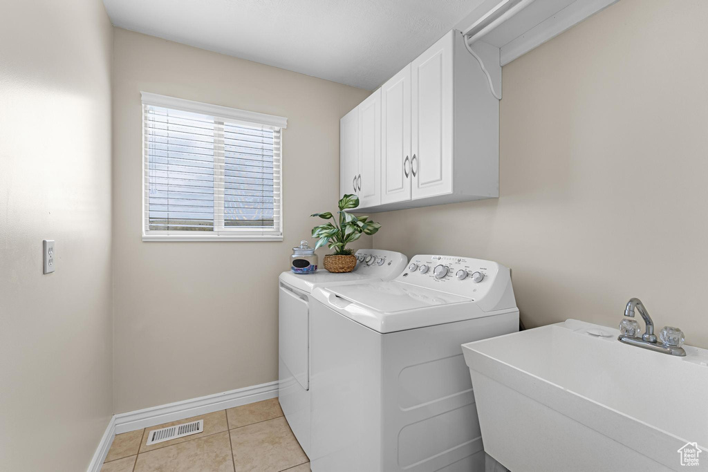 Washroom with washing machine and dryer, a sink, visible vents, baseboards, and cabinet space