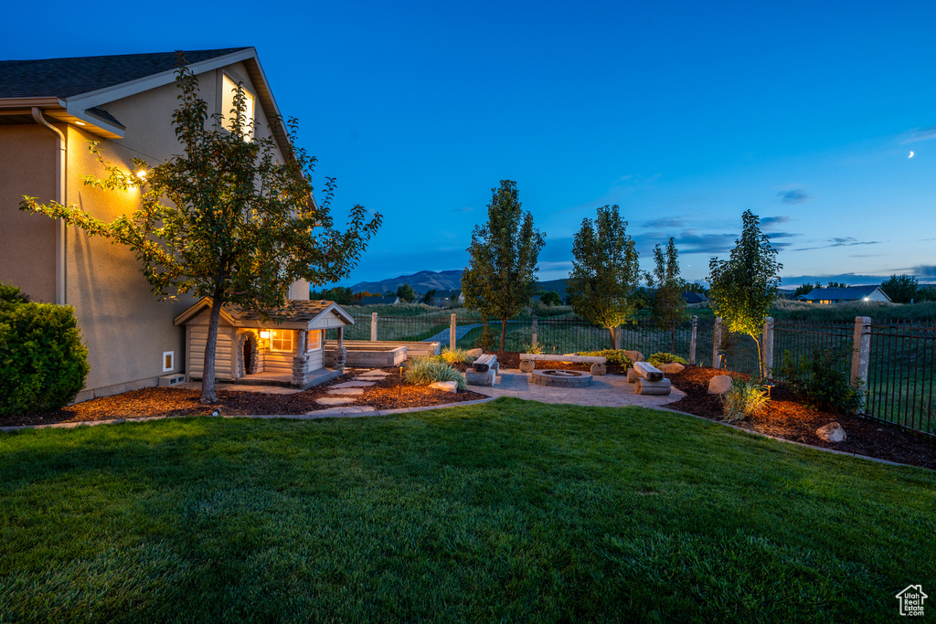 View of yard featuring a patio, a fire pit, fence, and a mountain view