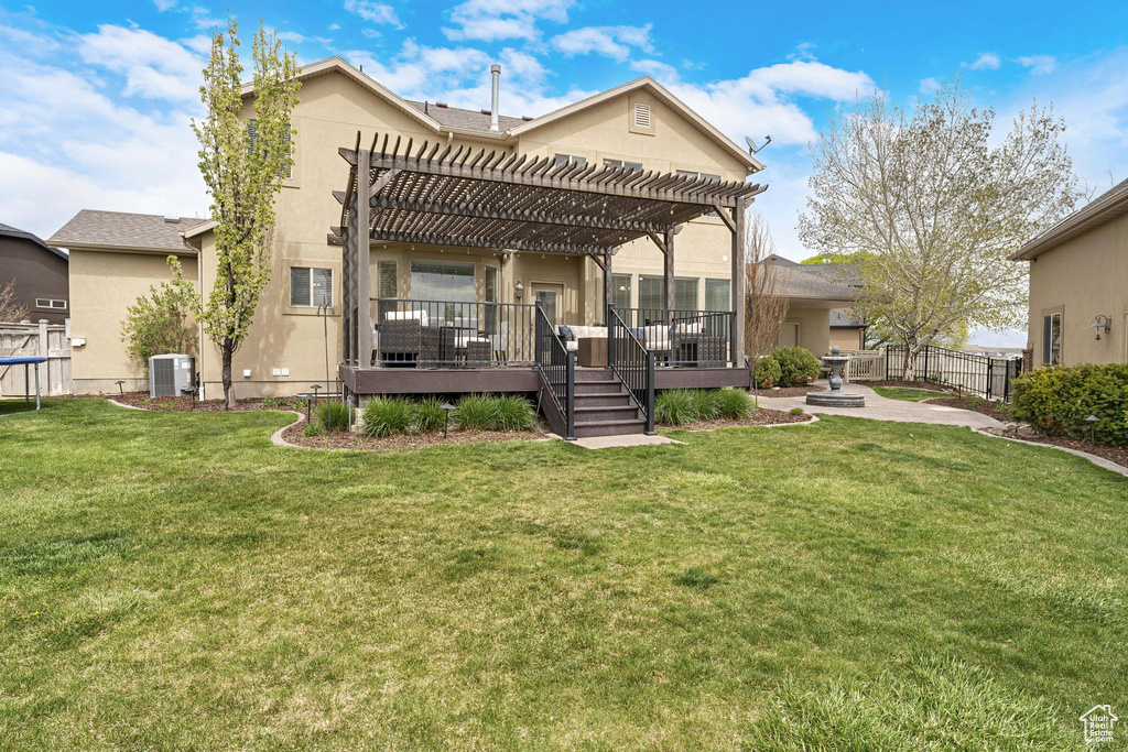 Rear view of property featuring stucco siding, a yard, fence, central AC unit, and a pergola
