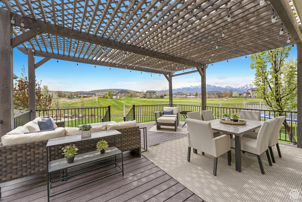 Wooden deck featuring outdoor dining space, a pergola, outdoor lounge area, and a mountain view