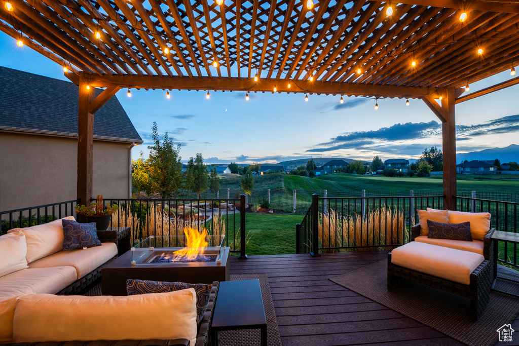 Wooden deck with an outdoor living space with a fire pit, a pergola, and a lawn