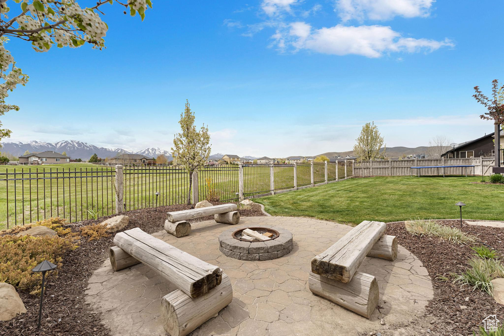 View of yard featuring a fire pit, a mountain view, a fenced backyard, and a patio area