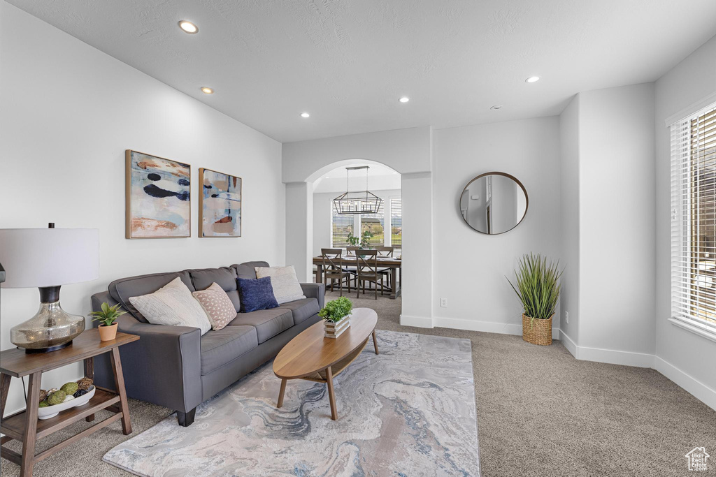 Carpeted living area featuring recessed lighting, arched walkways, and a healthy amount of sunlight