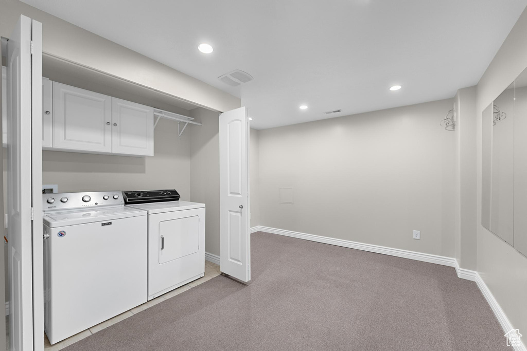 Clothes washing area featuring baseboards, washer and dryer, recessed lighting, light carpet, and laundry area