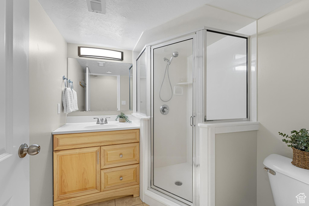 Bathroom with a shower stall, toilet, vanity, visible vents, and a textured ceiling