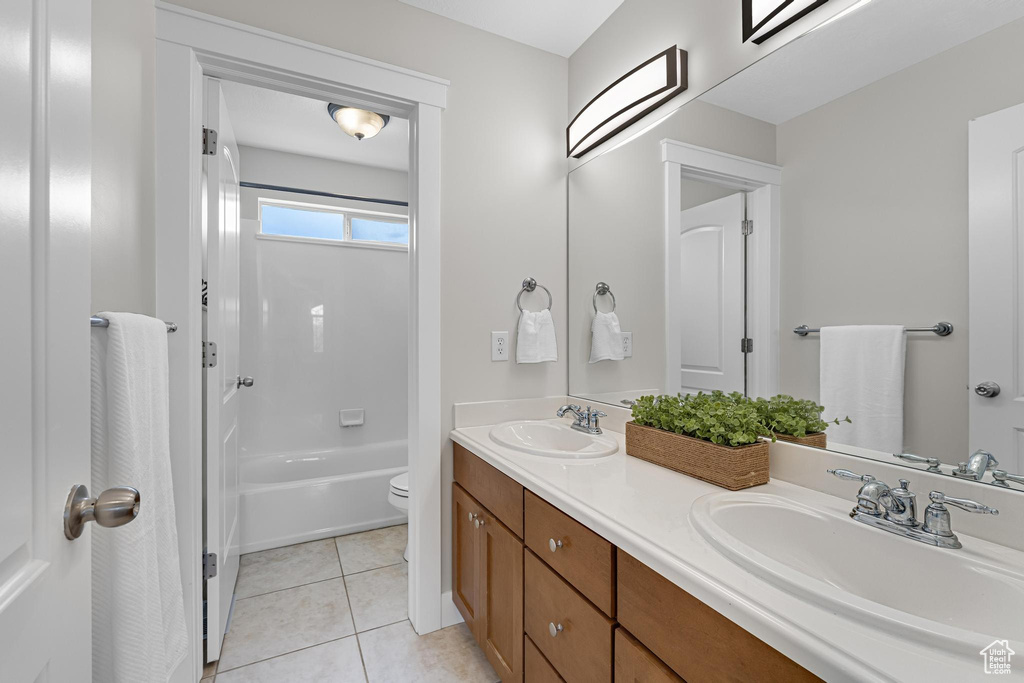 Full bathroom with toilet, tile patterned flooring, double vanity, and a sink