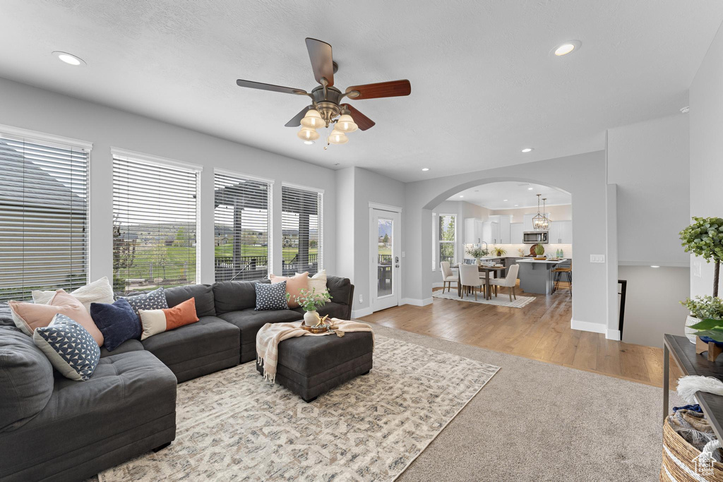 Living area with recessed lighting, arched walkways, ceiling fan, and a healthy amount of sunlight