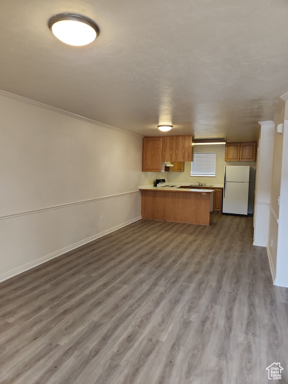 Kitchen featuring ornamental molding, freestanding refrigerator, a peninsula, brown cabinetry, and open floor plan