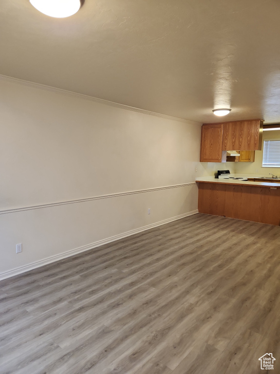 Unfurnished living room with baseboards, wood finished floors, and ornamental molding