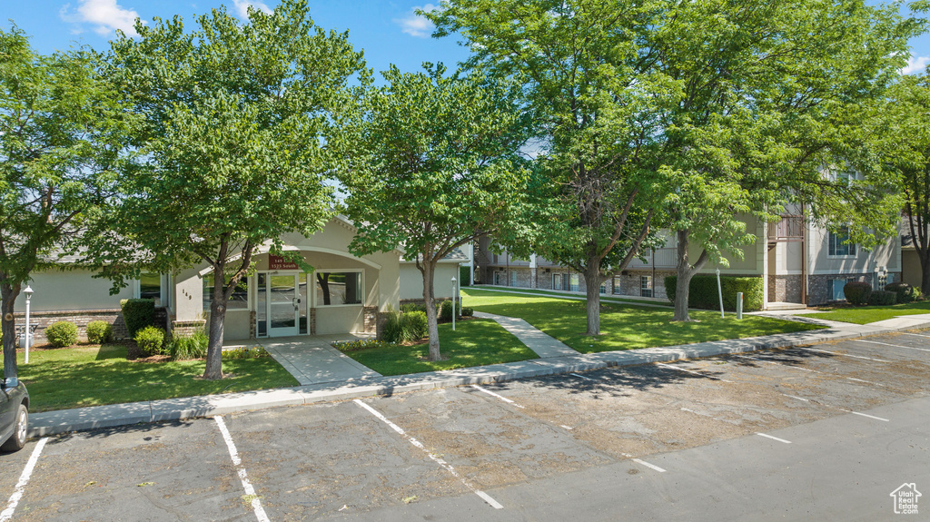 View of front of house featuring uncovered parking, a front lawn, stone siding, and stucco siding