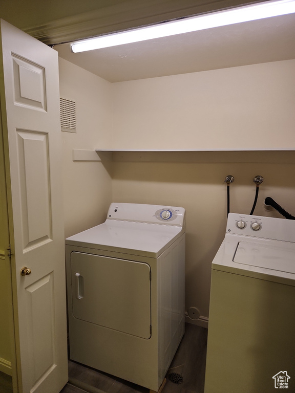 Clothes washing area with dark wood finished floors, separate washer and dryer, and laundry area
