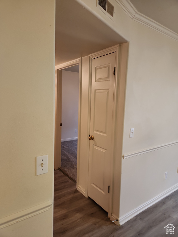 Hallway with ornamental molding, baseboards, dark wood-style flooring, and visible vents